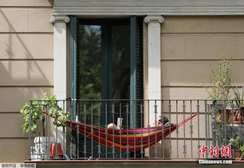 资料图：西班牙巴塞罗那居民在阳台上享受好天气。
