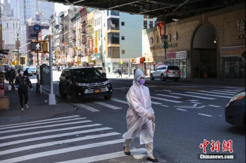 资料图：5月12日，纽约市曼哈顿唐人街，一名“全副武装”的女子正在过马路。中新社记者 马德林 摄