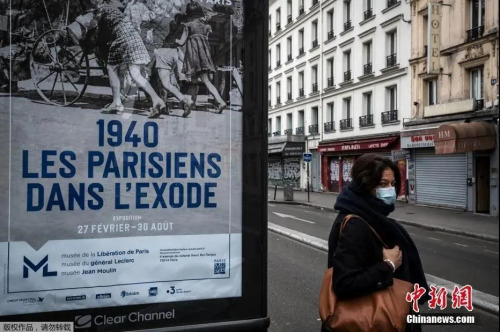 资料图：当地时间3月17日，法国巴黎，一名妇女戴着口罩步行在巴黎街头。