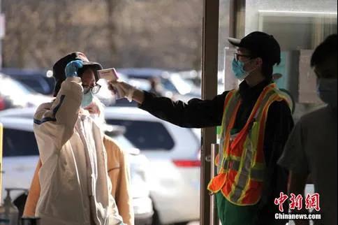 加拿大多伦多一家华人超市的工作人员在入口处对顾客逐一测量体温。(<a target='_blank' href='http://www.chinanews.com/'>中新社</a>记者余瑞冬摄)