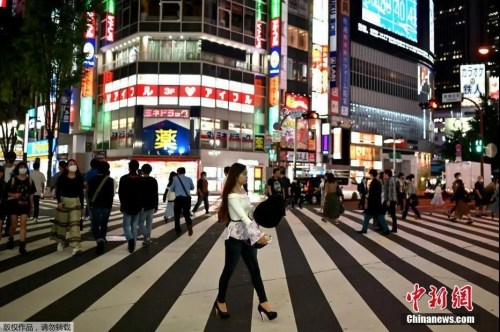 资料图：5月15日，日本解除紧急事态宣言，人们穿过东京新宿区的一条街道。（中新网）