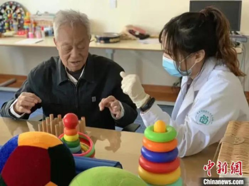资料图：北京一家社区养老服务中心内，工作人员与老人一起做游戏。　杜燕 摄
