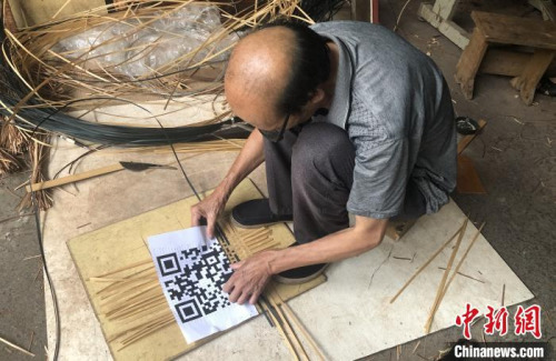 谢世仰将竹篾有序地摆在地上,对照着打印出来的二维码开始编织。 彭莉芳 摄 谢世仰将竹篾有序地摆在地上,对照着打印出来的二维码开始编织。 彭莉芳 摄