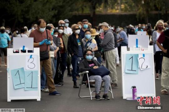 当地时间2021年1月13日，美国加利福尼亚州安纳海姆，美国加利福尼亚州橙县政府宣布，政府在当地迪士尼乐园度假区内安置了大型临时新冠疫苗接种点，位于园区东南部。据路透社11日报道，迪士尼接种点建成后，将成为橙县首个大规模疫苗接种点。加州迪士尼乐园自2020年3月份以来一直处于关闭状态，园方医疗主管帕梅拉·海默尔称，“能为抗疫工作做出贡献，我们非常荣幸”。图为人们在加州迪士尼乐园度假区接种疫苗的地点排长队等候。