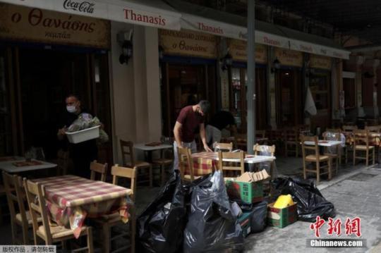 当地时间5月3日，希腊雅典，一家餐馆的服务生在收拾餐桌。