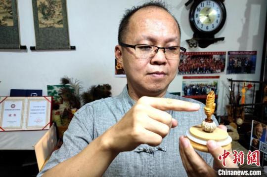 圖為黃樹立與核雕“火炬”作品。　梅鐿瀧 攝