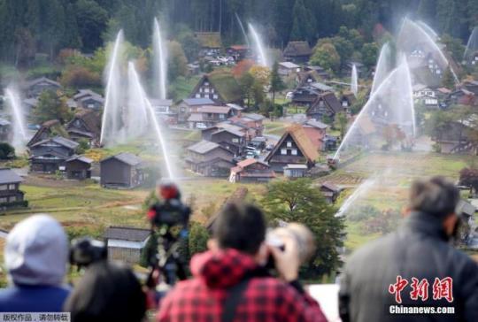 资料图：位于日本岐阜县白川村的白川乡合掌造村落举行放水演习，引来众多游客围观。