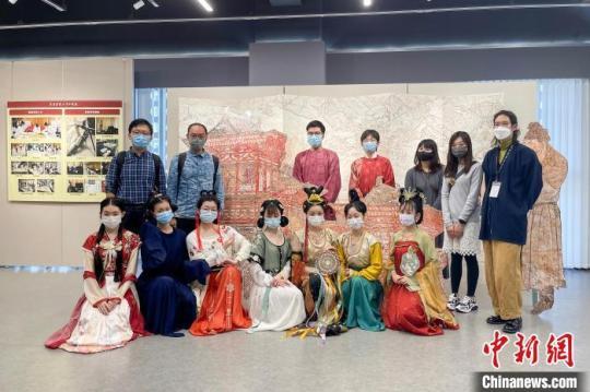 圖為澳門展中，身著唐裝的學(xué)子與精美的壁畫展陳合影?！≈袊螒c齡基金會供圖