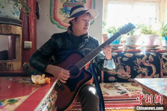 图为中国美术家协会会员、国家二级美术师李猛在西藏农牧民家里弹奏吉他。　江飞波 摄