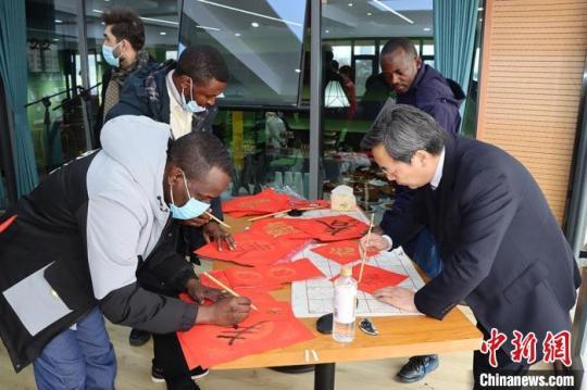 图为留学生和老师一起写“春”送祝福。　西北师范大学国际文化交流学院供图