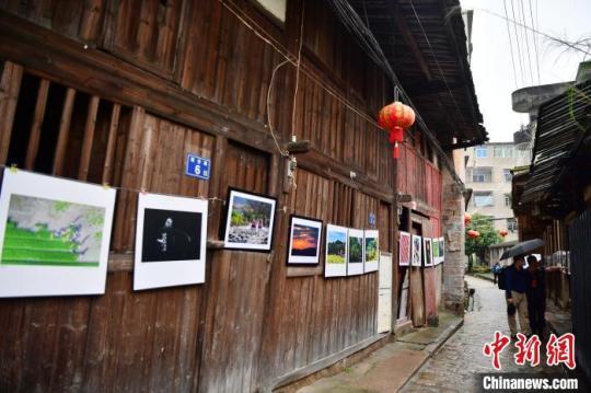 图为摄影爱好者在三溪村老街上观看展出的摄影作品。　张斌 摄