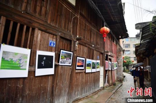 图为摄影爱好者在三溪村老街上观看展出的摄影作品。　张斌 摄