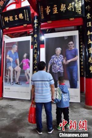 图为一位市民带着小孩在观看《父老乡亲——潘朝阳摄影作品展》。　张斌 摄
