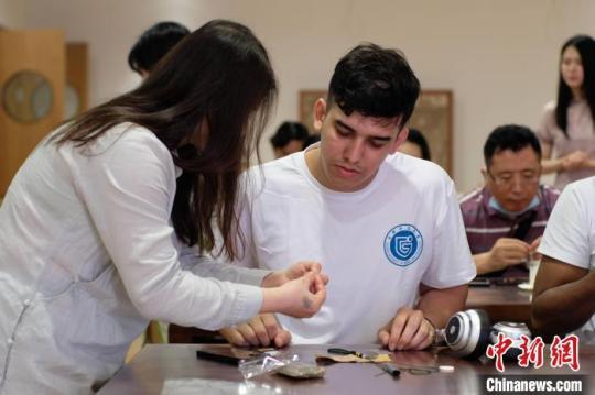 在老师的讲解下，国际友人正在学习缝制香囊。　刘俊聪 摄