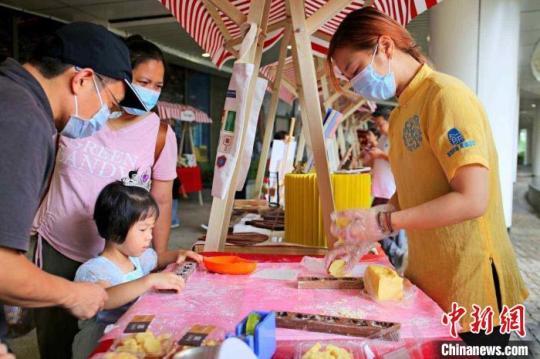 集市中，孩童学习广西传统糕饼制作。　蒙鸣明 摄