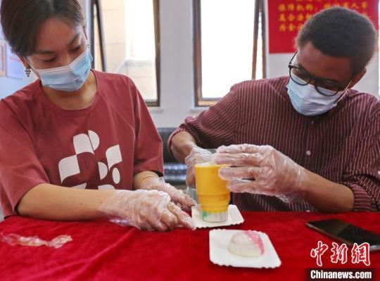 图为社区居民和外国留学生一起制作月饼。　曹建雄 摄