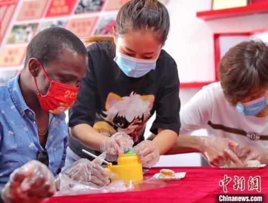 图为社区居民和外国留学生一起制作月饼。　曹建雄 摄