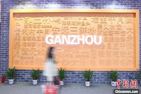 图为第五届赣菜美食文化节展区现场，市民从一面写有赣州特色美食名称的展示墙前走过。　刘力鑫 摄