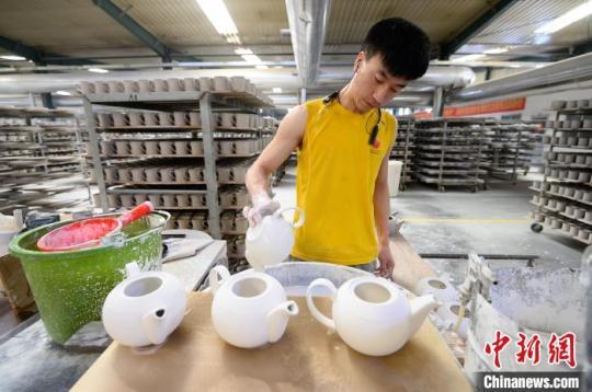 5月18日，山西省朔州市应县，博达瓷业有限公司工人在车间赶制手工茶壶订单，进行上釉作业。　韦亮 摄