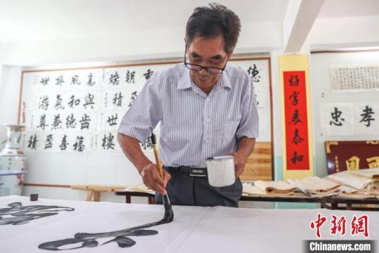 图为赣南客家匾额习俗的传承人肖天长在用毛笔写匾文。　刘力鑫 摄