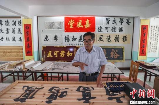 图为赣南客家匾额习俗的传承人肖天长在介绍客家匾额的制作工艺。　刘力鑫 摄