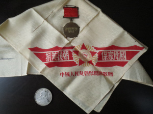 中国侨网周祝令珍藏60多年的3件纪念品：一枚抗美援朝纪念章、一方“抗美援朝、保家卫国”手帕和一块救命银元。（《青田侨报》）