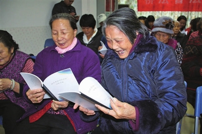 中国侨网大鹏新区居民开心翻看侨法宣传手册。(《深圳侨报》/林琳 摄)