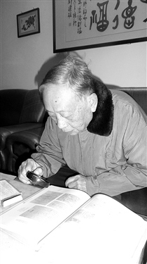 中国侨网张庆培拿着放大镜阅读93年前其父张葆琮的信件。(《梅州日报》/曾秋玲 摄)