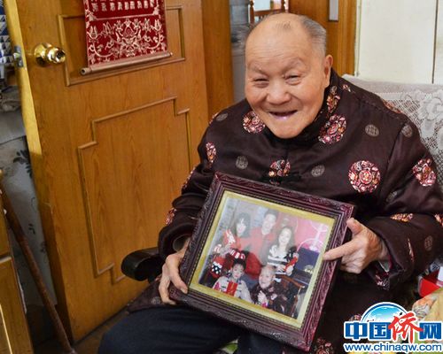 中国侨网家住北京东城区体育馆路街道的九旬侨眷老人房仲孝向记者展示他和儿孙的合影。杨凯淇 摄