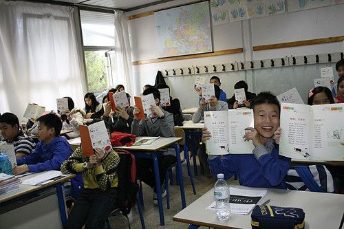 中国侨网图为佛罗伦萨中文学校学生兴奋地翻看着一本本散发着油墨香味的《温州童谣》