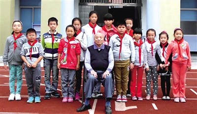 中国侨网周克信老人与龙背小学的孩子们在一起合影留念。