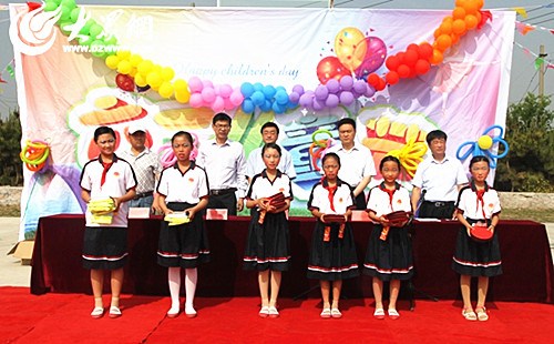 中国侨网山东省日照市侨联携手侨企慰问侨心小学，向学生代表发送荧光衣、笔记本等用品。