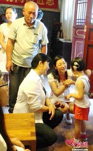 中国侨网河南省侨联董锦燕主席（前左一）、管城区侨联白梅主席在为孩子佩戴助听器。