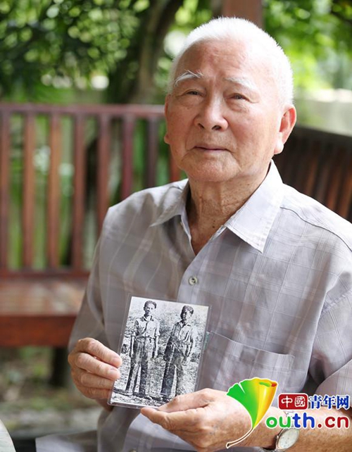 86岁的王声手拿13岁时参加抗日远征军的照片(左侧为其本人)，向记者讲述少年参军抗日的烽火岁月。中国青年网记者