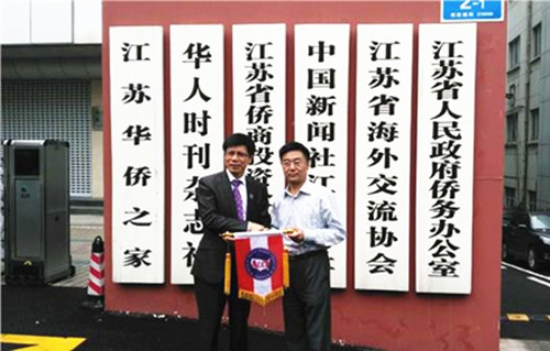 美国中餐联盟主席朱天活向江苏省侨办副主任孙彬赠送美国中餐联盟会旗。