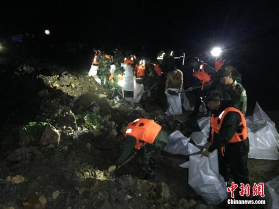 9月28日,17号台风“鲇鱼”在福建登陆,受其影响,浙江多地发生多起泥石流、洪涝、滑坡等灾害。当地公安、消防、武警等多部门联合救援。图为:武警官兵正在装填搬运沙袋加固堤坝。中新社记者