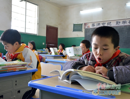 中国侨网万载县马步乡后塘小学的学生正坐在精美的新课桌前读书。