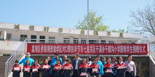 中国侨网考察团成员为千朗沟小学学生发放助学款。