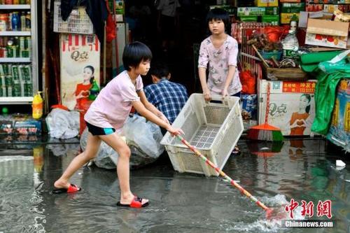 中国侨网资料图：9月3日，广东汕头市瓦窑村，两名女孩协助家长清理商铺外的积水。当日，广东汕头市潮南区天气转好，内涝地区积水水位逐渐下降。中新社记者 陈骥旻 摄