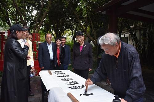 中国侨网在清水塘社“侨胞之家”调研时,隋军等观看社区居民汪建国老人书写“社区为侨 侨爱社区”条幅。(湖南省侨联网站)