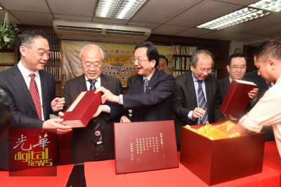 中国侨网黄惠康在吴骏领事陪同下向许廷炎等展示四库全书。（马来西亚《光华日报》）