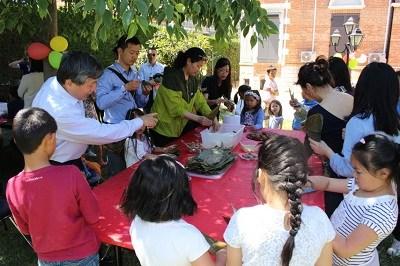 中国侨网中文学校老师为学生们示范包粽子