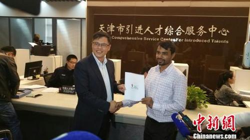 中国侨网资料图:天津市外国专家局局长袁鹰(左)为南开大学克鲁迪普博士颁发天津首张《外国人工作许可证》。 刘家宇 摄