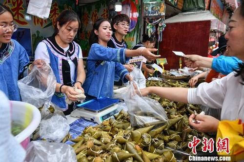 中国侨网资料图:6月5日,商贩身穿少数民族服饰售卖特色粽子。中新社记者 任东 摄