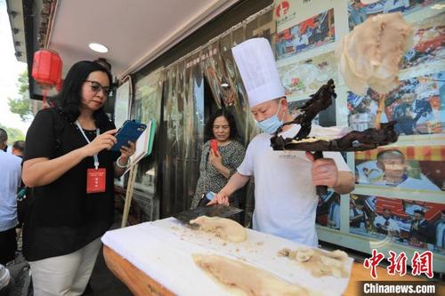 中国侨网“行走中国·2023海外华文媒体高层川渝行”参访团拍摄李庄白肉等特色美食。　王磊　摄