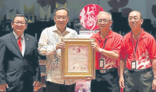 乐团指导林朝星（右起）及音乐社署理社长罗石盛从主办单位接收奖状。（马来西亚《南洋商报》）
