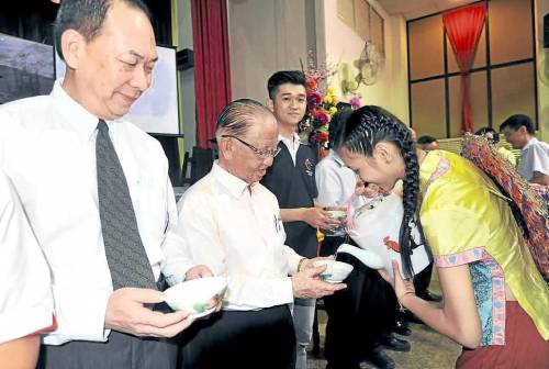 舞蹈员倒三宝井的水供嘉宾饮用,左起陈南益及林源瑞。(马来西亚《南洋商报》)
