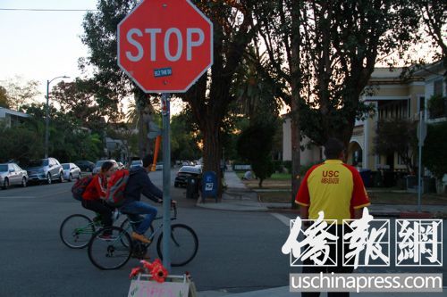 2名中国留学生骑车在“小黄衣”旁边经过。（美国《侨报》/周慧一