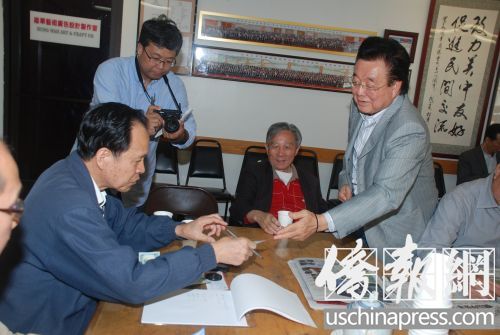 吴国宝向华商总会办公室主任雷荣畅递交其捐款支票。(美国《侨报》/吴卓明