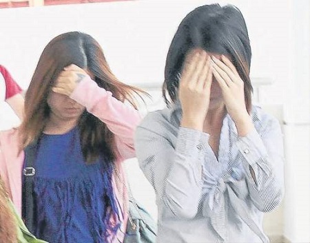 女被告李淑燕（前），双手遮脸避开镜头。（马来西亚《南洋商报》）